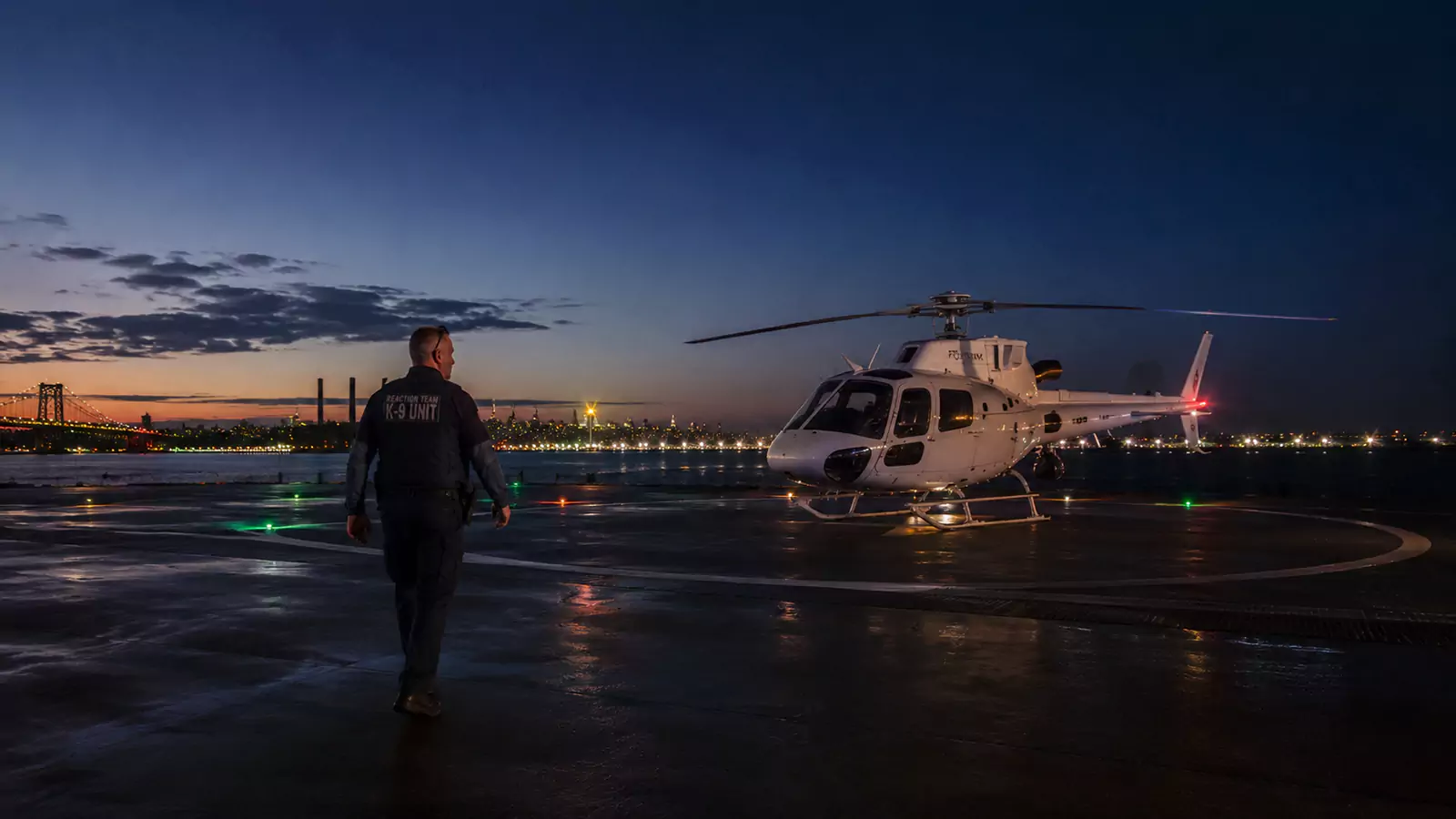 A man walking towards a helicopter on a runway.