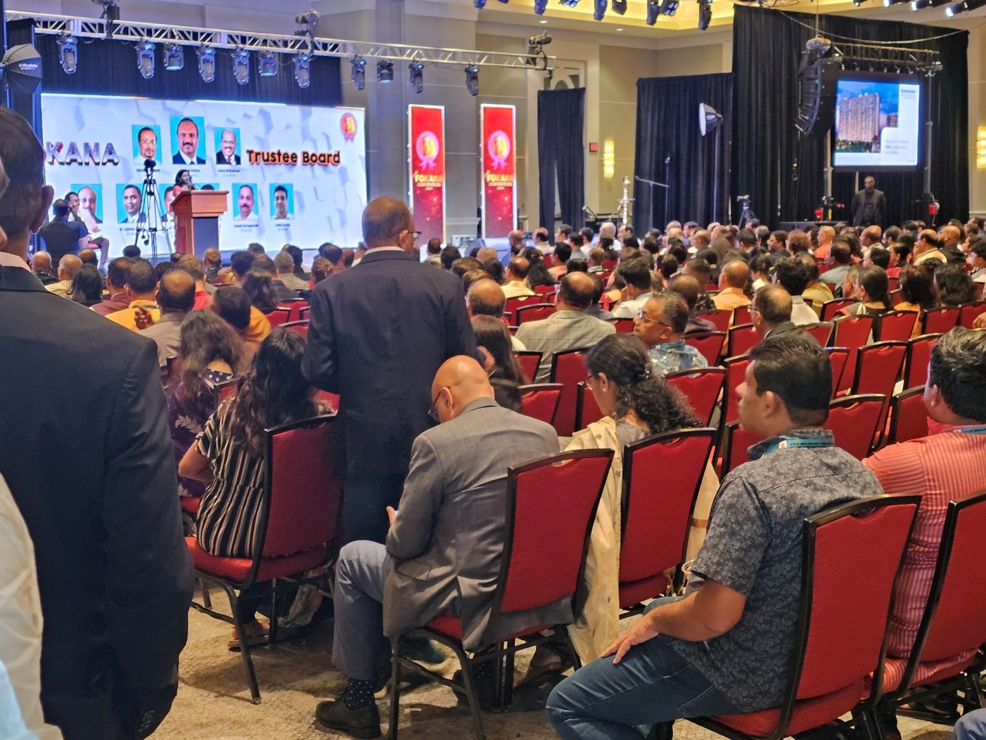 A large crowd of people sitting in red chairs.