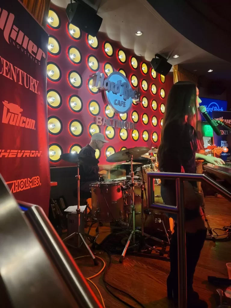 A dark room with a band and a woman playing a keyboard.