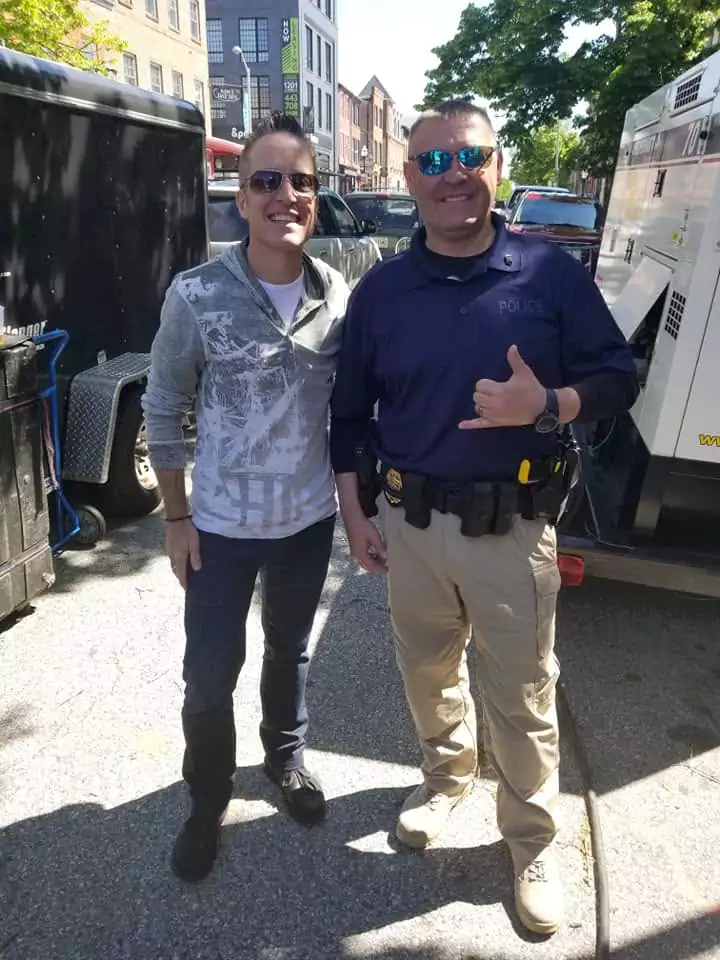 Two men walking down a street with their thumbs up.