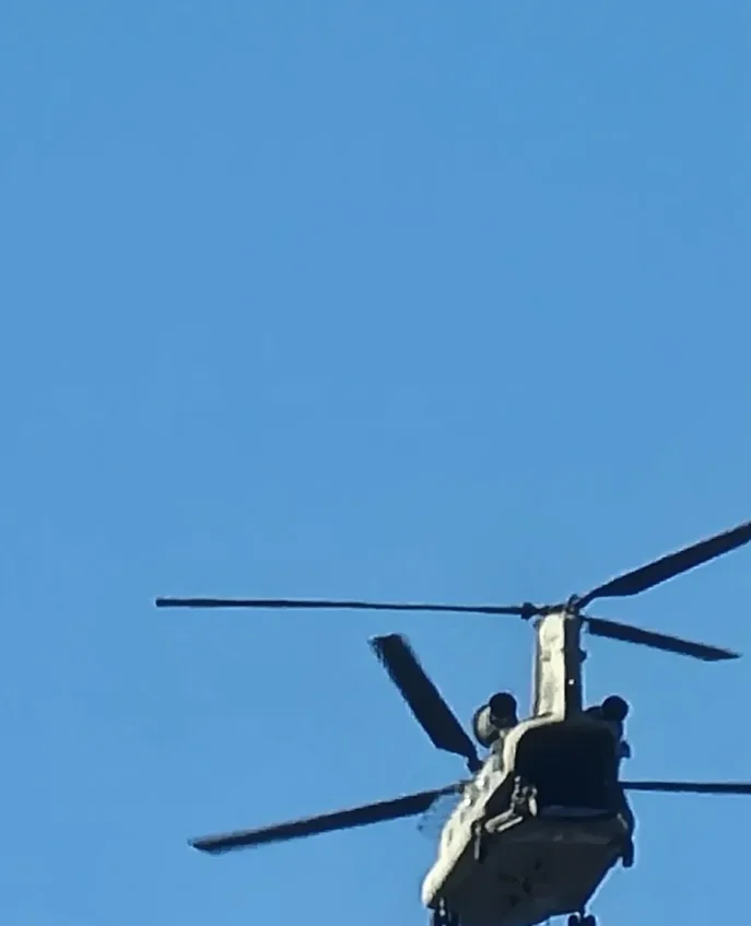 A helicopter flying through the air with a blue sky behind it.