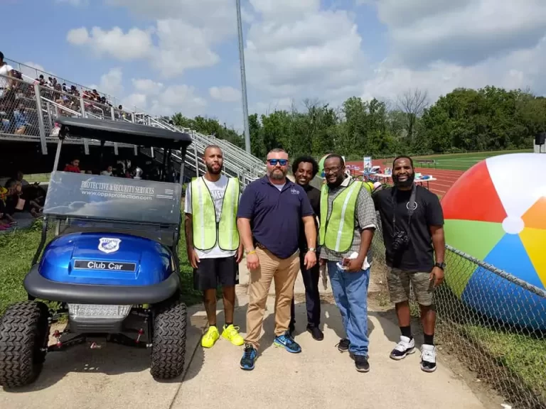 A group of men standing next to a blue car.