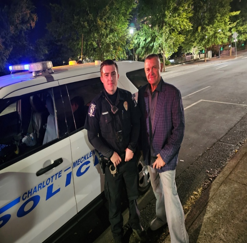 Two men standing next to a police car.